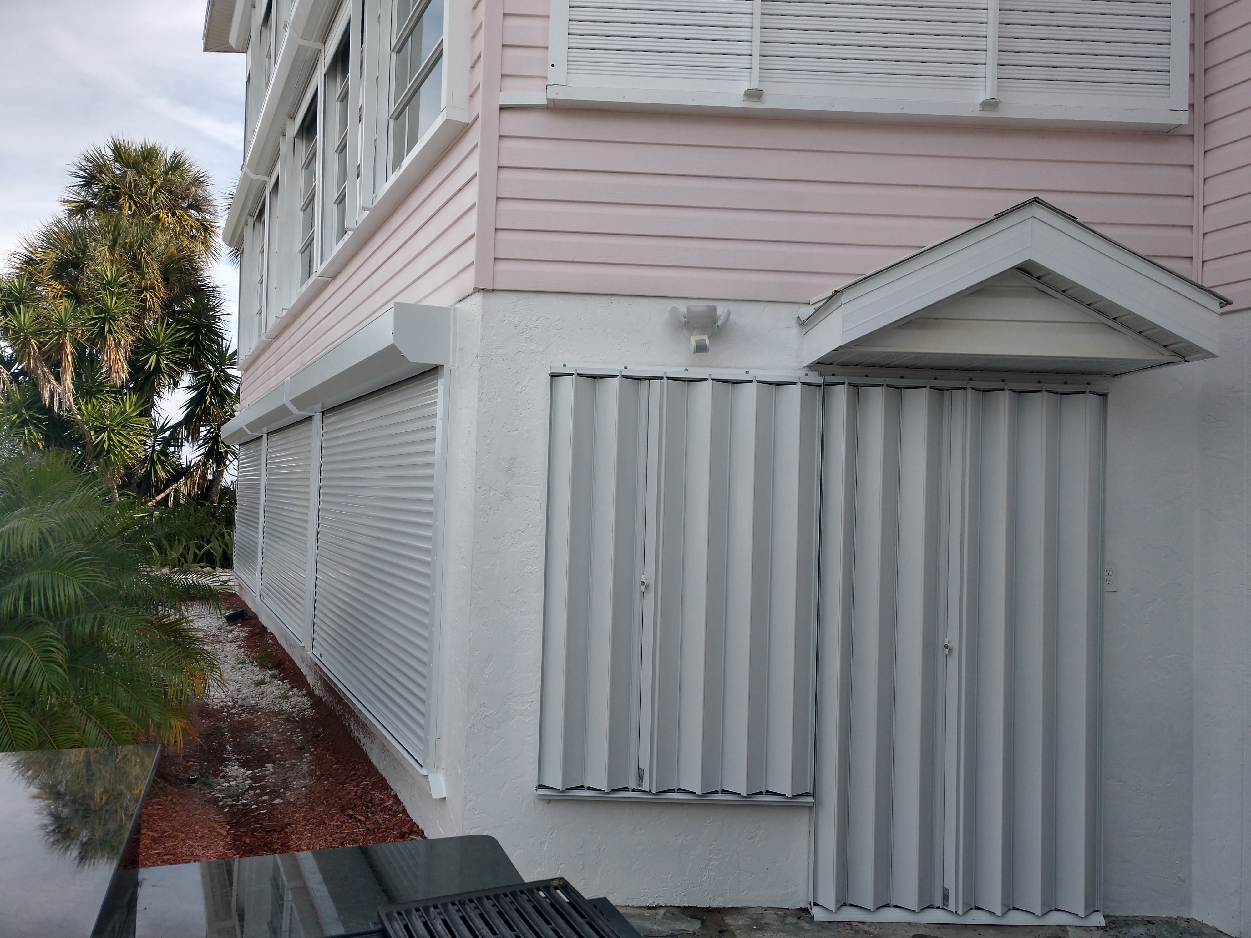 Accordion shutters on doors and roll-down shutters on windows of a Sarasota island home