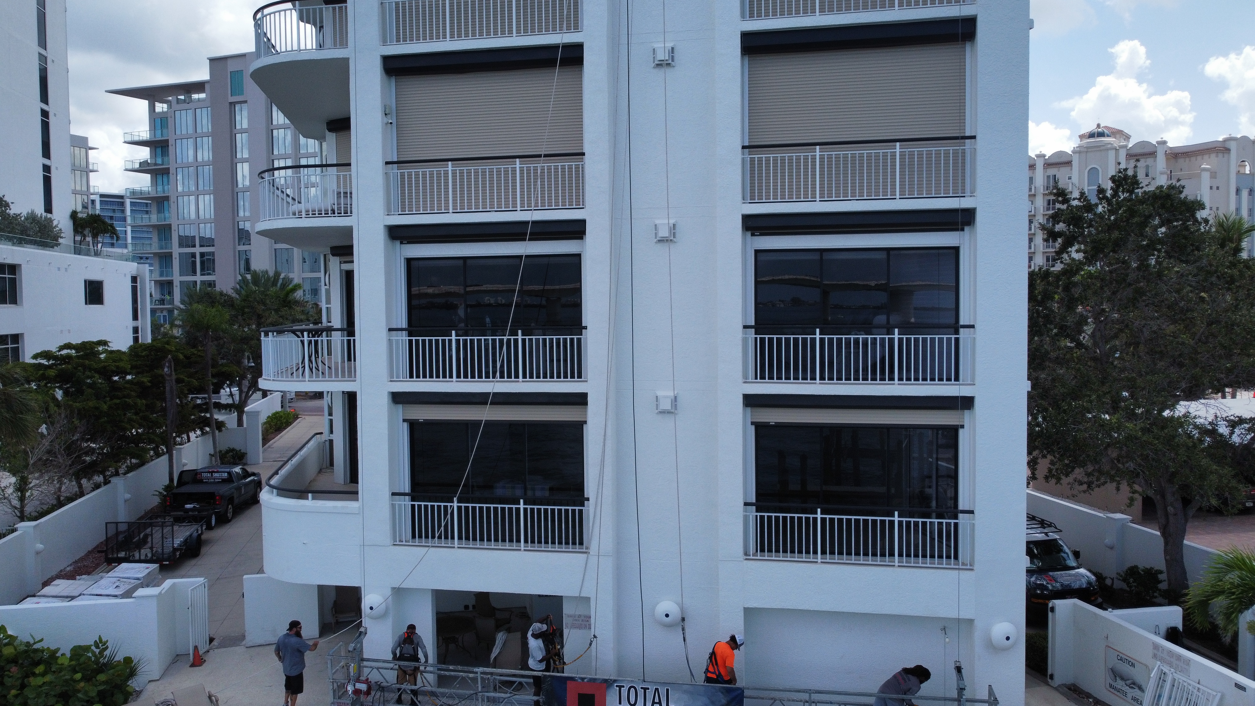 Aerial view of a Sarasota condo building with hurricane shutters installed on every unit