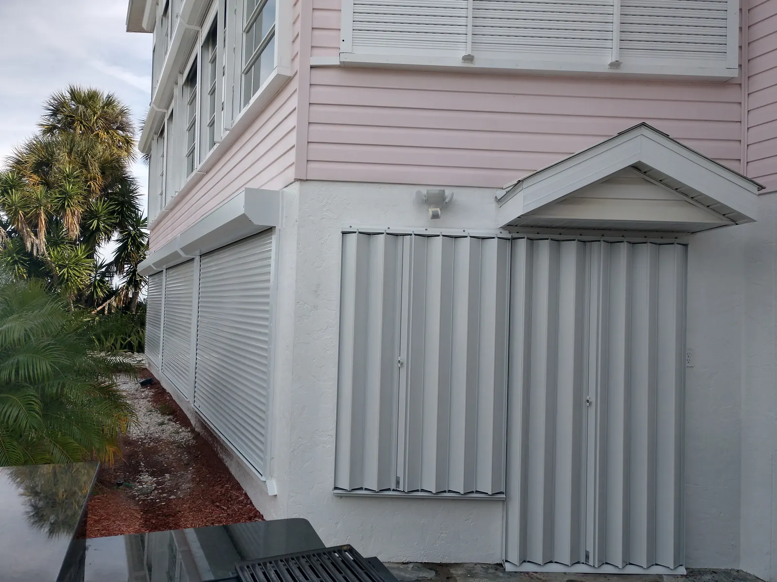 Accordion shutters on doors and roll-down shutters on windows of a Sarasota island home