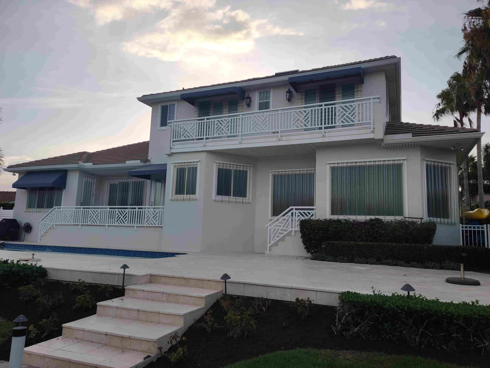 Two-story luxury Sarasota waterfront home with blue Bahama hurricane shutters throughout